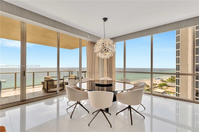 tiled dining room featuring a notable chandelier, a water view, and a view of the beach