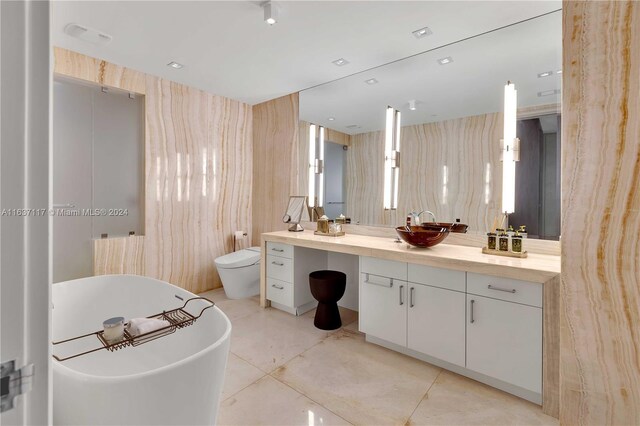 bathroom featuring toilet, tile patterned floors, vanity, and a bathtub