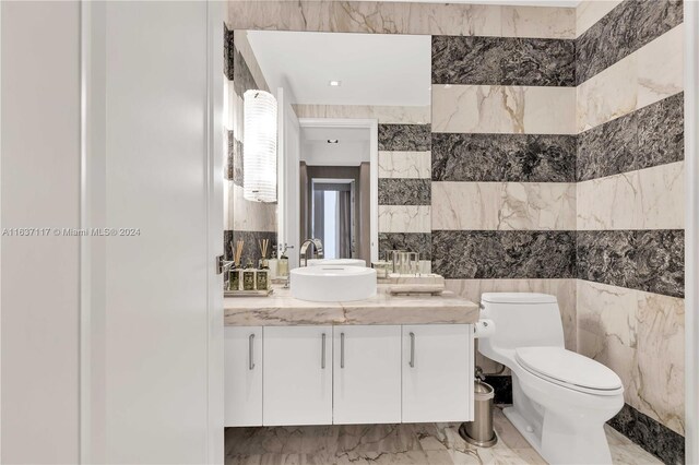 bathroom featuring tile walls, vanity, tile patterned flooring, and toilet