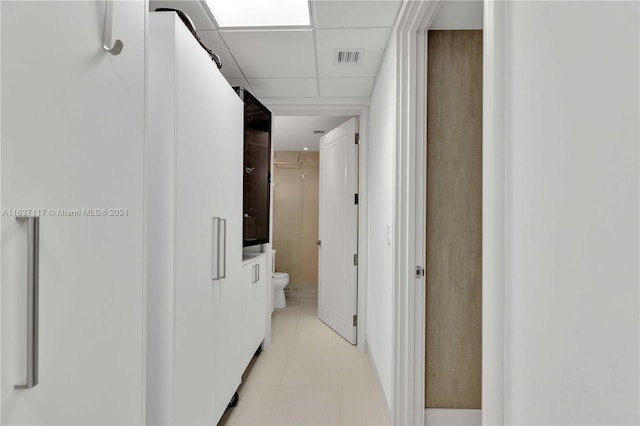 hallway with a paneled ceiling and light tile patterned floors