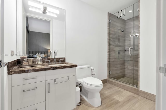 bathroom with a shower with shower door, vanity, and toilet