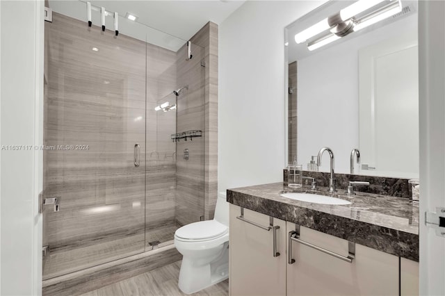 bathroom featuring toilet, vanity, and an enclosed shower