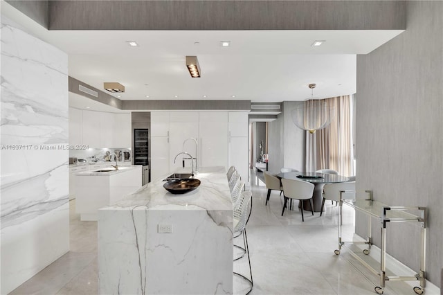 kitchen featuring white cabinetry, pendant lighting, a center island with sink, light tile patterned floors, and sink