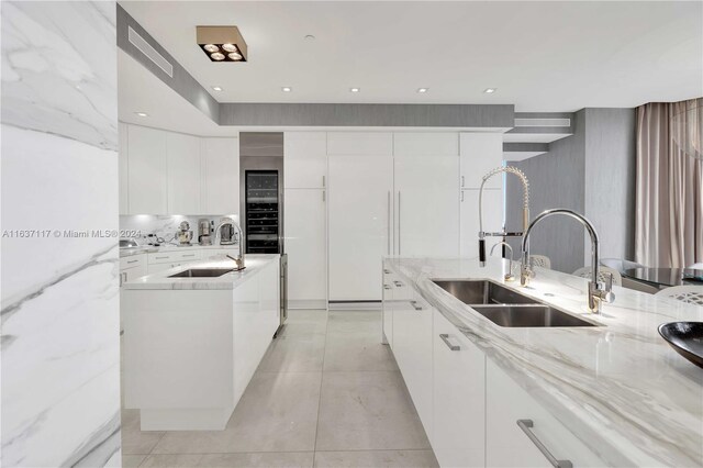 kitchen featuring light tile patterned flooring, sink, and white cabinetry