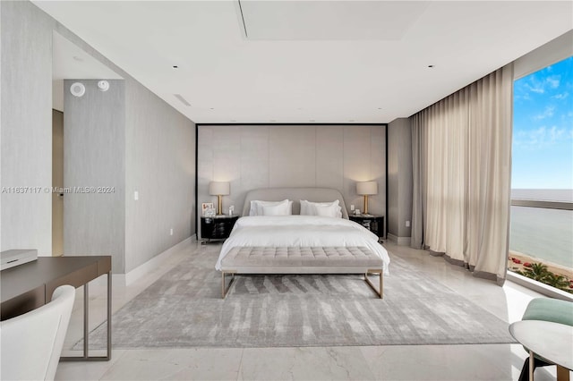 bedroom featuring light tile patterned floors, floor to ceiling windows, and a water view