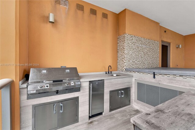 kitchen featuring light hardwood / wood-style flooring, fridge, and sink