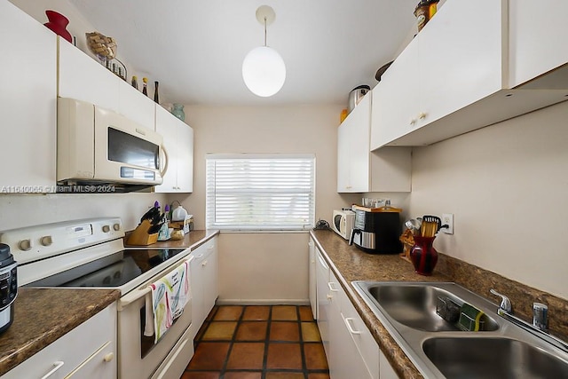 kitchen with dark tile patterned flooring, white appliances, sink, and white cabinets