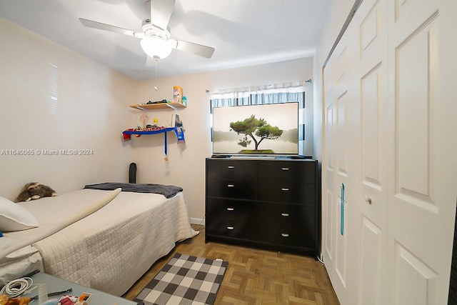 bedroom featuring ceiling fan, a closet, and parquet floors