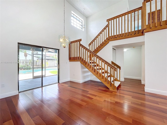 interior space featuring wood-type flooring, a high ceiling, and a chandelier