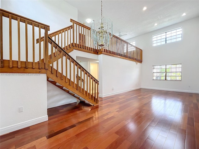 interior space with a notable chandelier, a towering ceiling, hardwood / wood-style flooring, and a textured ceiling