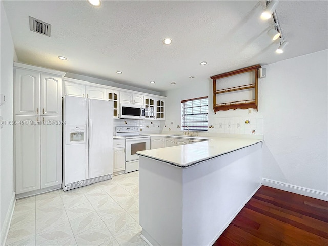 kitchen featuring tasteful backsplash, kitchen peninsula, light hardwood / wood-style floors, white appliances, and sink