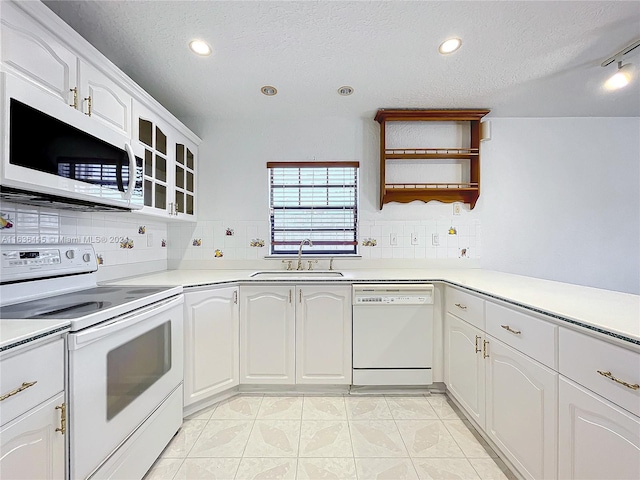 kitchen featuring tasteful backsplash, white appliances, a textured ceiling, light tile patterned floors, and sink