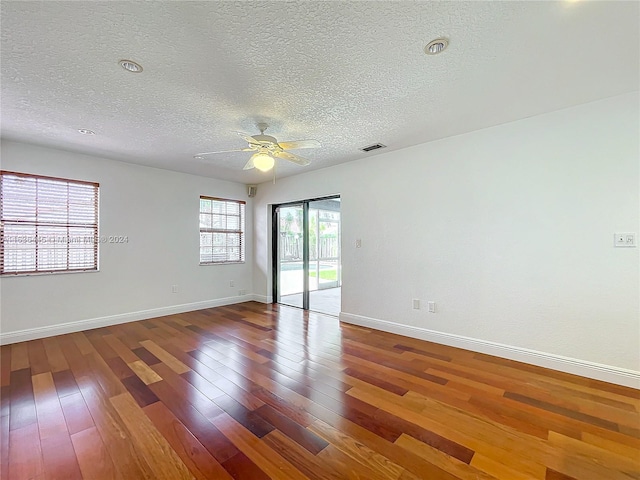 empty room with ceiling fan, a textured ceiling, and hardwood / wood-style floors