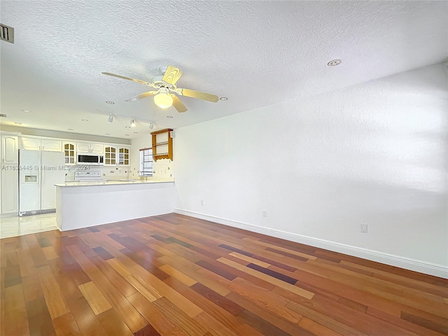 unfurnished living room with ceiling fan, light tile patterned flooring, a textured ceiling, and rail lighting