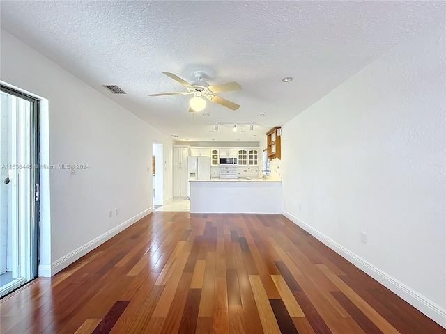 unfurnished living room featuring a textured ceiling, hardwood / wood-style floors, ceiling fan, plenty of natural light, and rail lighting