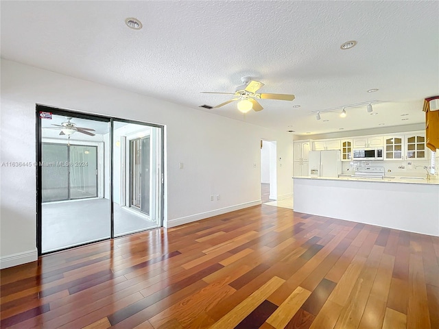 unfurnished living room with ceiling fan, track lighting, a textured ceiling, and hardwood / wood-style floors