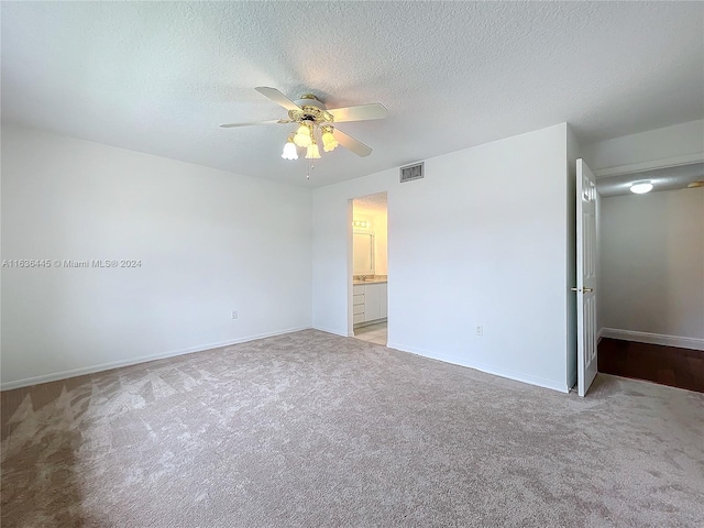 unfurnished bedroom with ceiling fan, a textured ceiling, light colored carpet, and ensuite bathroom