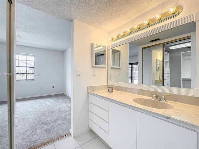 bathroom with a textured ceiling, tile patterned floors, and vanity