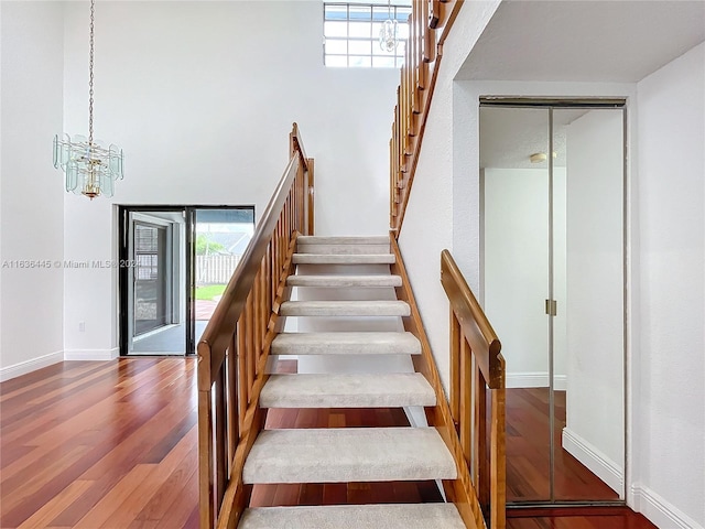 stairway with wood-type flooring and a chandelier