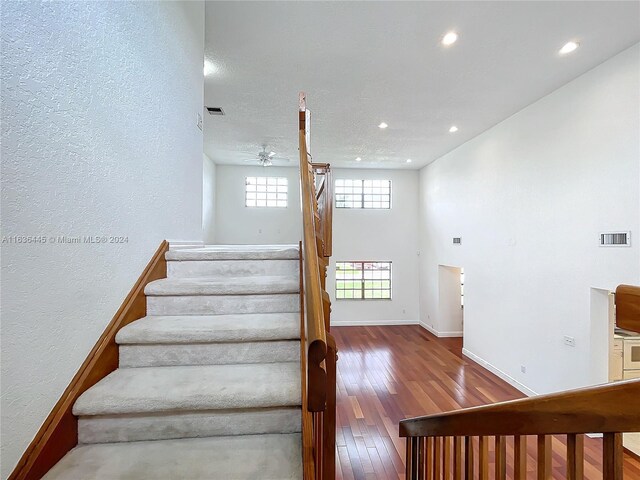 staircase with ceiling fan and hardwood / wood-style flooring