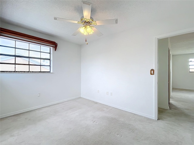 unfurnished room with ceiling fan, a textured ceiling, a healthy amount of sunlight, and carpet floors