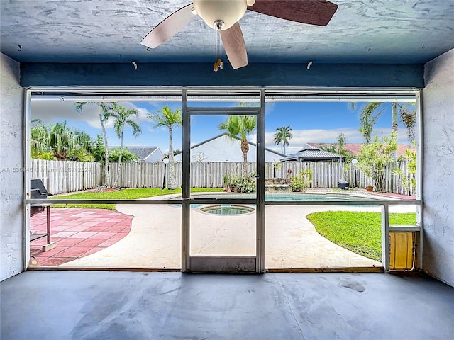 doorway to outside featuring concrete floors, ceiling fan, and a healthy amount of sunlight