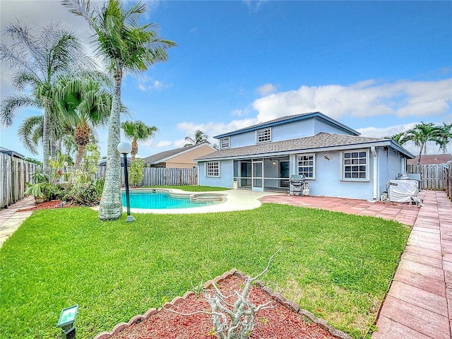 rear view of property with a yard, a patio, and a fenced in pool