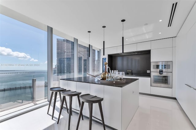 kitchen with white cabinetry, double oven, plenty of natural light, pendant lighting, and a kitchen island