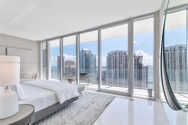 bedroom featuring a water view, multiple windows, and expansive windows