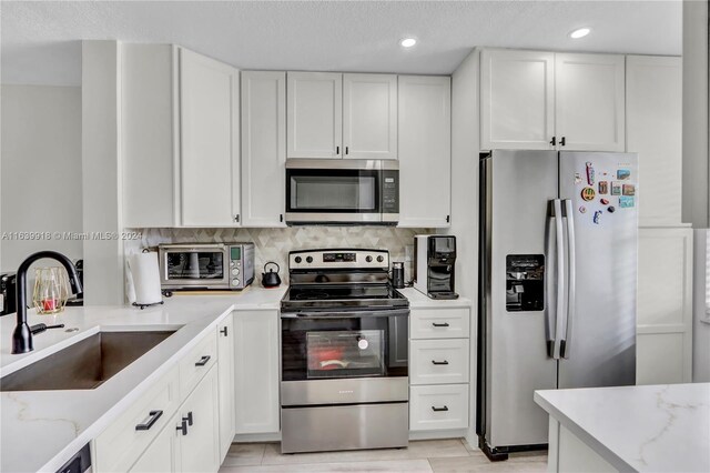 kitchen featuring appliances with stainless steel finishes, sink, and white cabinetry