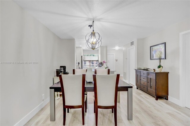 dining space featuring light wood-type flooring and an inviting chandelier