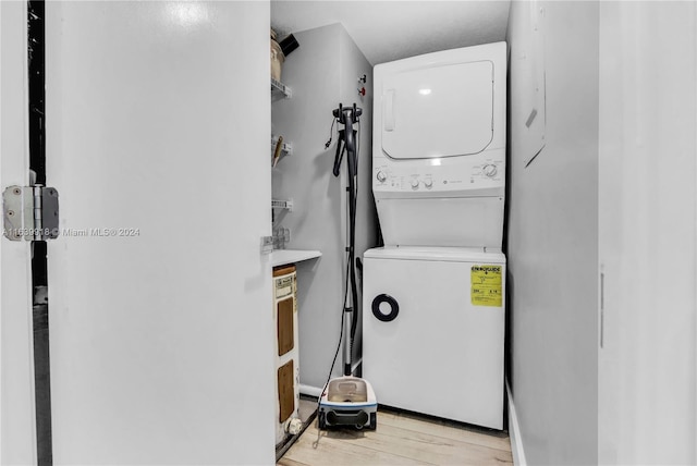 laundry area featuring stacked washer / dryer and light hardwood / wood-style floors