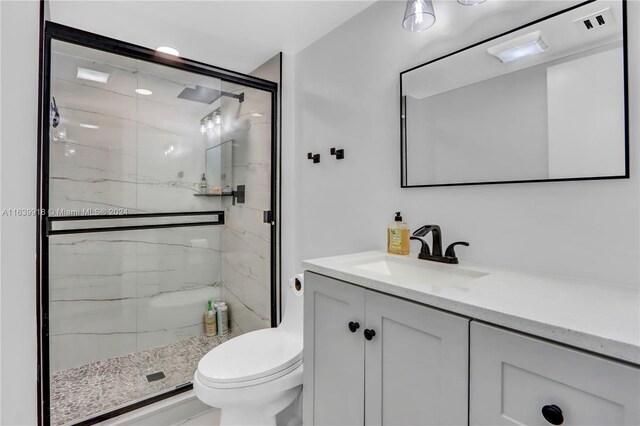 bathroom with toilet, vanity, and an enclosed shower