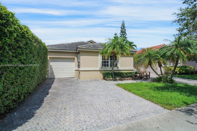 single story home featuring a garage, a tiled roof, decorative driveway, and stucco siding