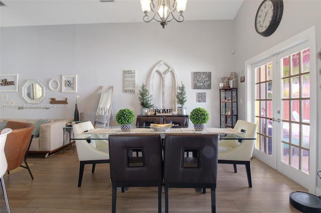 dining area featuring french doors, wood finished floors, and an inviting chandelier