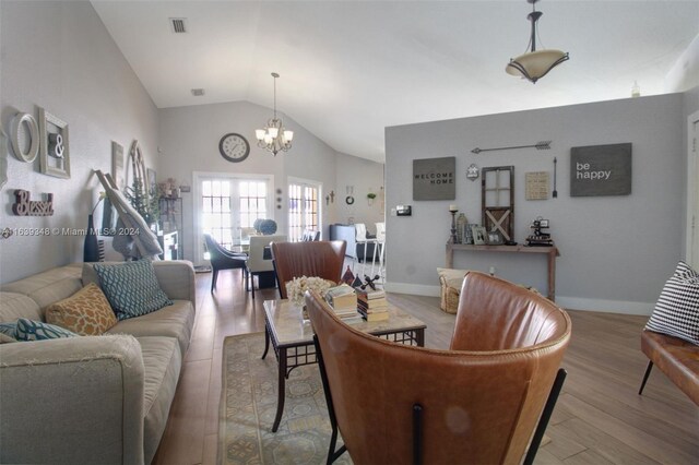 living room with an inviting chandelier, light wood-type flooring, and lofted ceiling