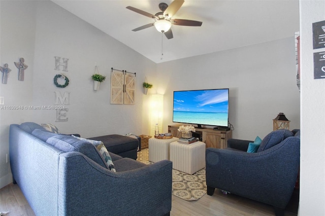 living room with a ceiling fan, vaulted ceiling, and light wood-style flooring