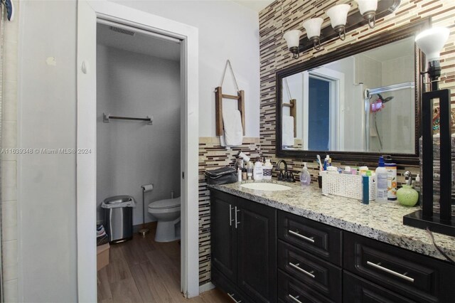 bathroom featuring vanity, toilet, hardwood / wood-style floors, and backsplash