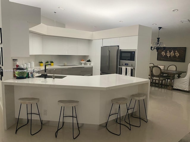 kitchen featuring a breakfast bar area, sink, tasteful backsplash, white cabinetry, and black appliances