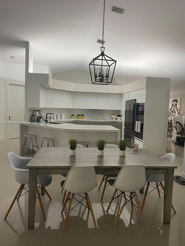 kitchen with decorative light fixtures, light tile patterned floors, a notable chandelier, backsplash, and black fridge