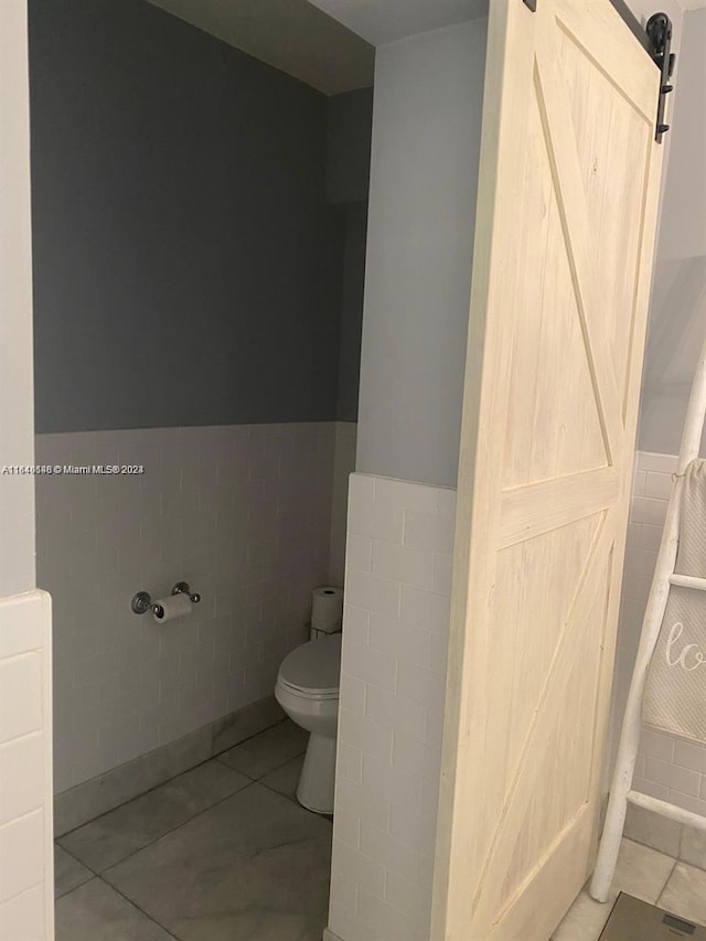 bathroom featuring tile patterned floors, tile walls, and toilet