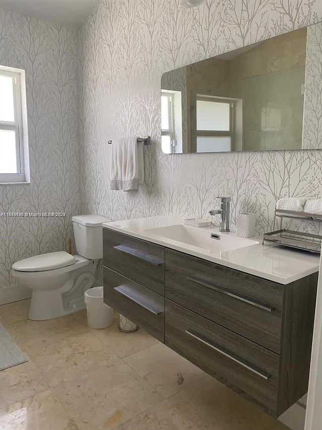 bathroom with toilet, vanity, and tile patterned flooring