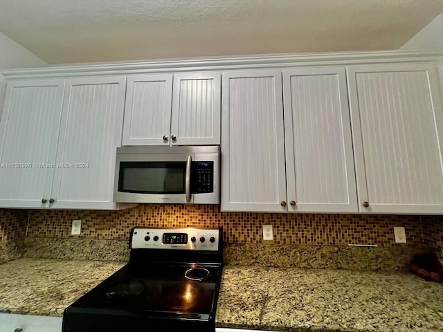 kitchen with light stone counters, white cabinetry, backsplash, and appliances with stainless steel finishes