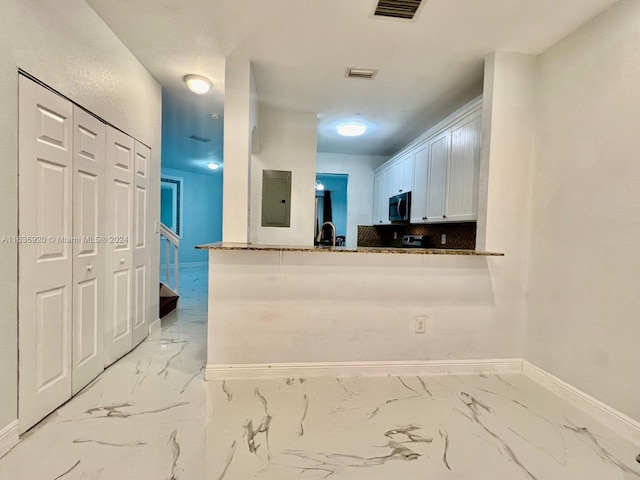 kitchen with electric panel, white cabinets, sink, decorative backsplash, and kitchen peninsula