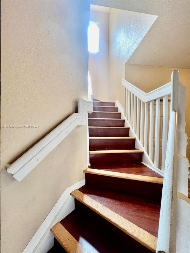 staircase featuring a textured ceiling