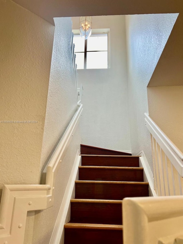 stairway featuring a chandelier