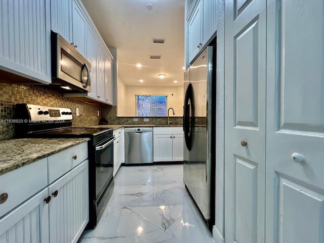 kitchen with white cabinetry, sink, light stone counters, backsplash, and appliances with stainless steel finishes