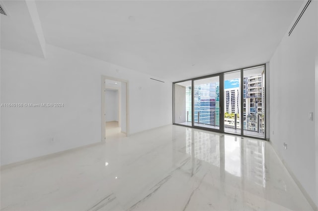 spare room with tile patterned floors and a wall of windows