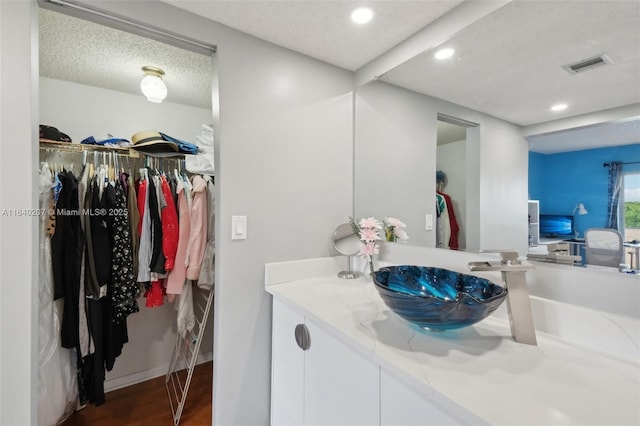 bathroom with hardwood / wood-style floors, vanity, and a textured ceiling