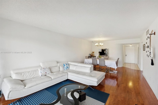 living room featuring hardwood / wood-style floors, a textured ceiling, and a notable chandelier